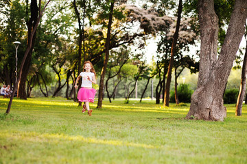 Naklejka premium haired little girl runs across the grass