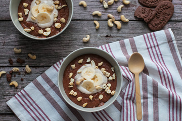Chocolate cereal with bananas and nuts on the table with a wooden spoon