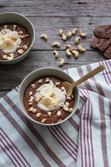 Chocolate cereal with bananas and nuts on the table with a wooden spoon