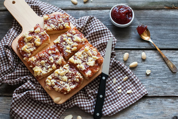 chopped shortbread with jam and cashew nuts on a board and a napkin