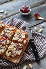 chopped shortbread with jam and cashew nuts on a board and a napkin