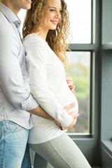 Happy and young pregnant couple in studio, white background