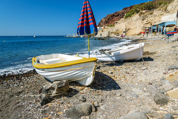 Old boats and umbrella on the beach of Santorini island, Greece