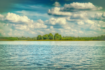 Summer landscape with cumulus clouds on the lake. Retro filter and vintage style.