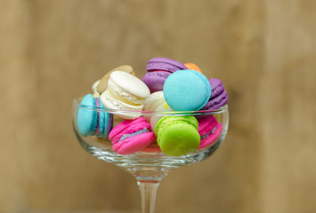 colorful macaroons in glass on wooden table