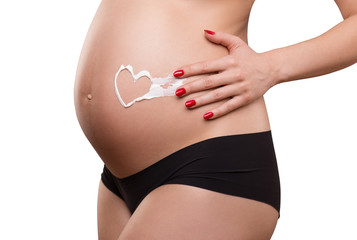 pregnant woman applying cream on her belly, skin care, heart