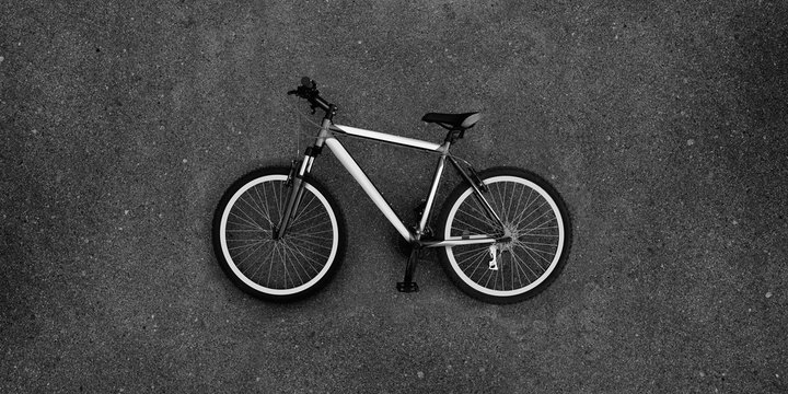 Super large photo of bike lying on the pavement. Bicycle in black and white color. Real asphalt texture background. Best way show postcard with this velo. Velocipede on grey asphault textured surface.