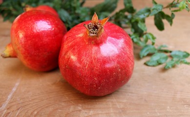 Pomegranate ripe juicy fruits on the wooden table with leaves