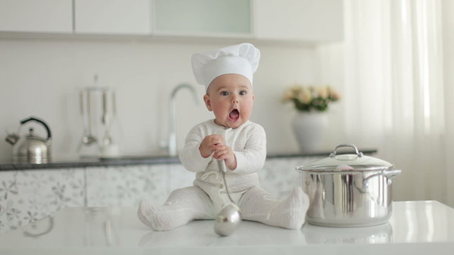 Toddler sitting on a table with a saucepan and ladle