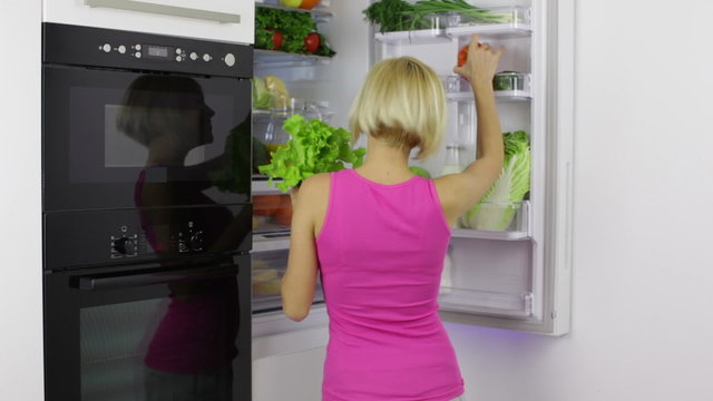 woman take vegetables from refrigerator excited