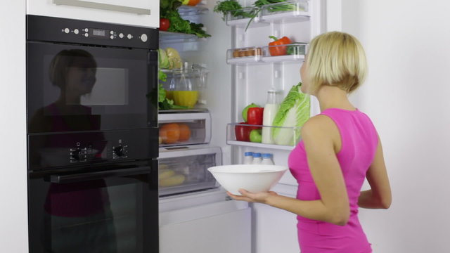 woman bowl take raw fresh vegetables from refrigerator