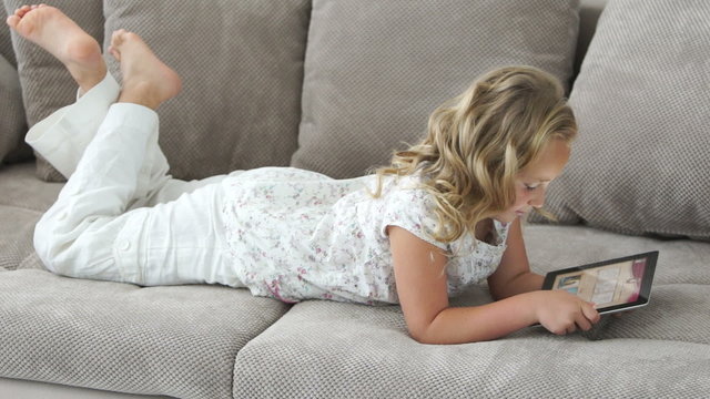 Cute girl with tablet pc lies on the couch