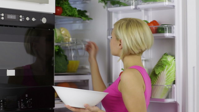 woman hold bowl take raw fresh vegetables from refrigerator