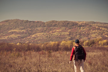 Fototapeta na wymiar Male tourist with backpack sotret on the horizon in autumn
