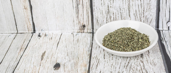 Dried basil leaves herbs over in white bowl over wooden background