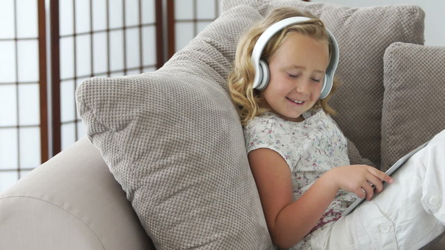 Little girl listening to music and looking at camera with a smile
