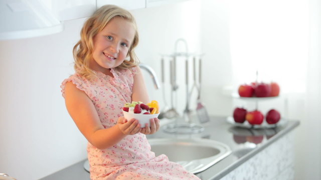 Lovely girl holding a plate of fruit yogurt and smiling