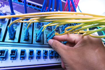 man working in network server room with fiber optic hub for digi