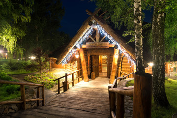 Wooden cottage in forest lit by lanterns