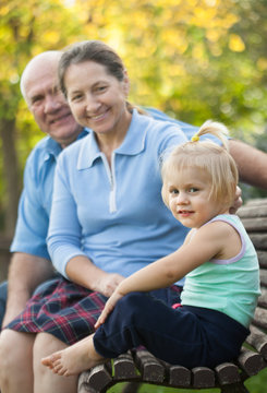 mature couple with child sitting on bench