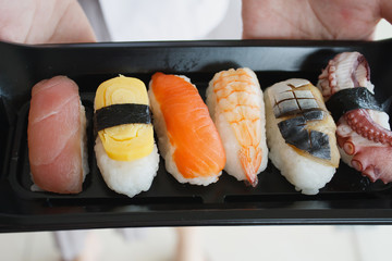 Woman hands holding plate of sushi