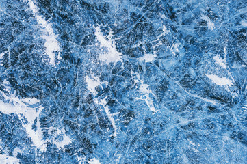 Blue ice with cracks and bubbles on the frozen lake.