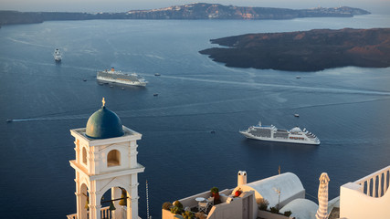 View from highest point in village of Imerovigli, in Santorini, Greece, with cruise ships anchored and small boats bringing tourists ashore. © ANADMAN