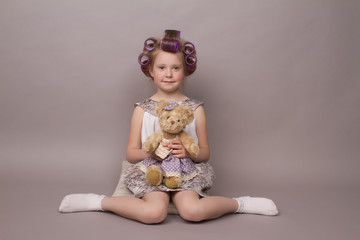 the little girl in hair curlers looks in the camera and sits