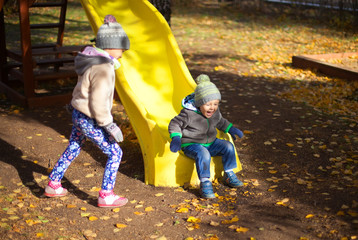 Children playing with autumn fallen leaves in park