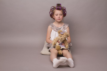 the little girl in hair curlers looks in the camera and sits
