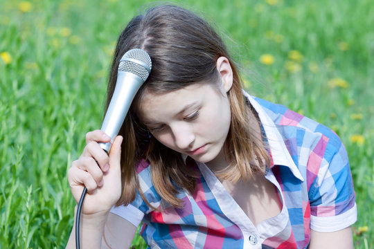 Portrait of sad pensive teen girl with microphone in hand