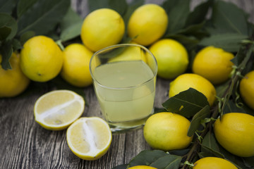Fresh juicy lemons and a glass of homemade lemonade on a wooden background