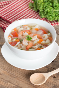 Macaroni with shrimp soup on white bowl.