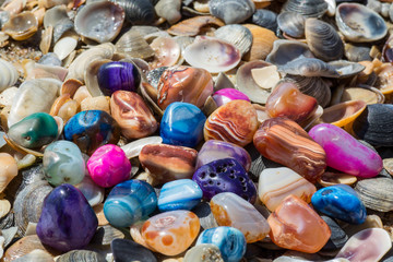 Multicolored agates with seashells on the beach