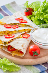 Quesadilla with sour cream, salad and tomatoes