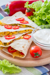 Quesadilla with sour cream, salad and tomatoes