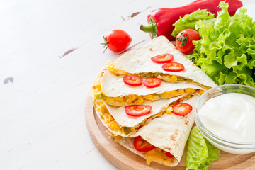 Quesadilla with sour cream, salad and tomatoes