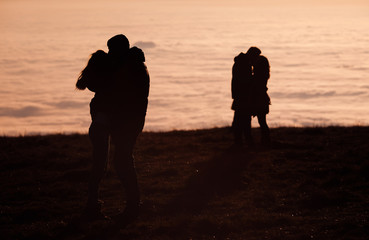 silhouetted couples kissing above inversion fog