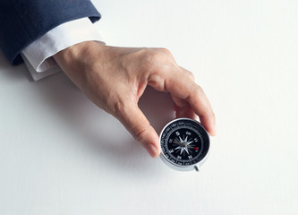Businessman with a compass holding in hand on paper background © ipopba
