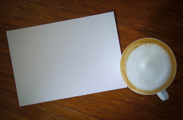 Cup of hot coffee and watercolor paper on the wooden table