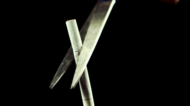 Scissors cutting a cigarette in half