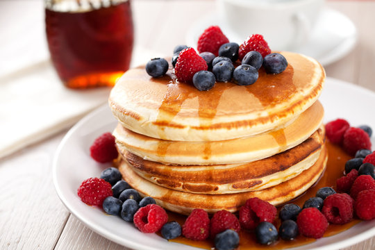 Pancakes with berries and maple syrup.