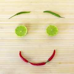Decorative composition with healthy eating smiling face from vegetables and fruits on bamboo background. Image of natural materials. Eco style.