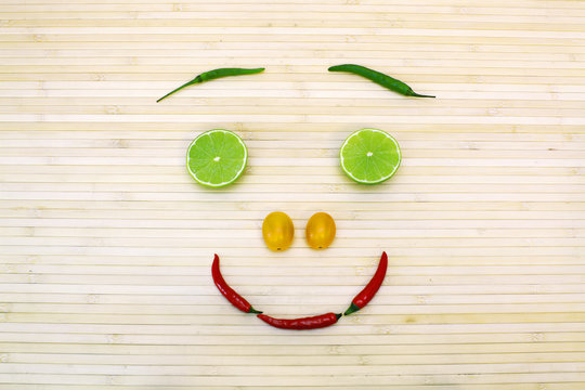 Fanny composition with healthy eating smiling face from vegetables and fruits on bamboo background. Image of natural materials. Eco style.