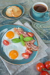 Fried eggs,  bacon, tomato, toast and a cup of coffee