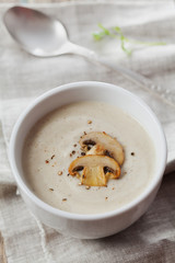 Fototapeta na wymiar Cream soup with mushrooms champignon and potato in white bowl, vintage style, top view