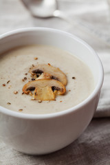 Cream soup with mushrooms champignon and potato in white bowl, vintage style