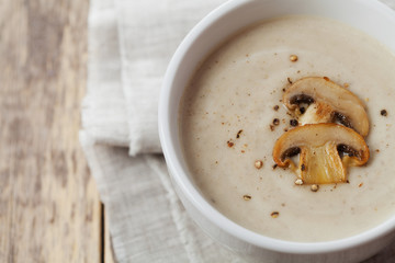 Cream soup with mushrooms champignon and potato in white bowl, vintage style