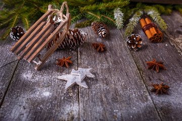 Xmas or new year composition with holiday decoration - sledge and fir branches, pinecones on wooden background. Xmas card. Space for text. Vintage style