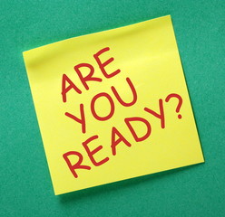 The question Are You Ready in red text on a yellow sticky note attached to a green notice board as...
